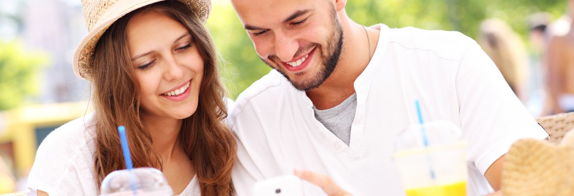 A picture of a happy couple using smartphone in a cafe