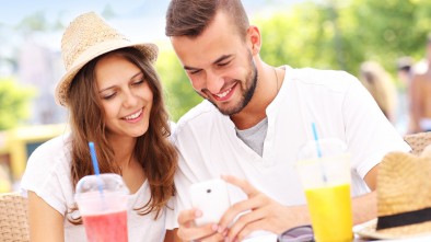 A picture of a happy couple using smartphone in a cafe